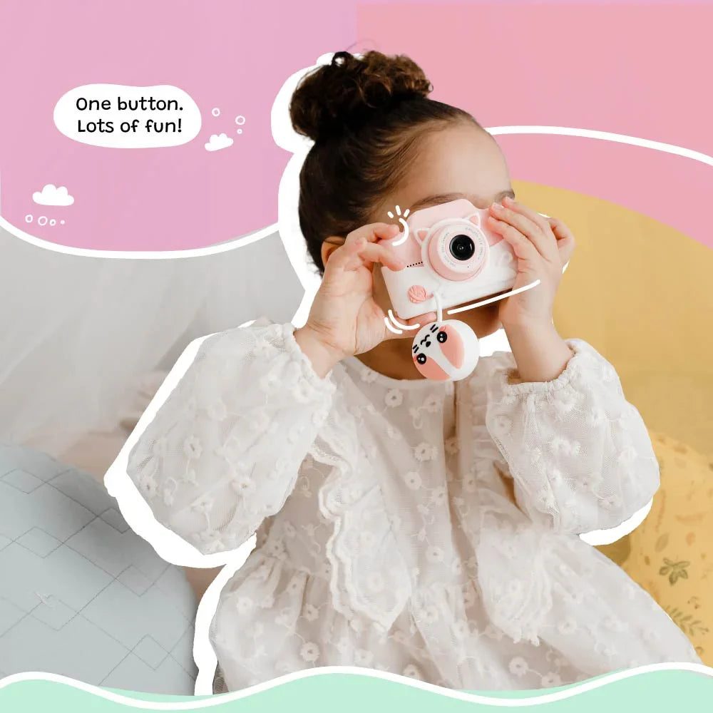 Little girl using the kiimento Meowie the Cat digital camera, pressing the shutter button to capture fun moments with its adorable pink silicone design.