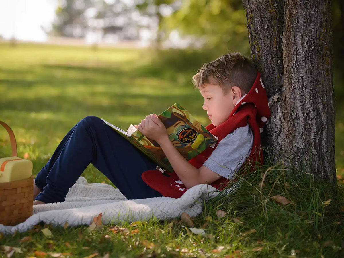 Child reading a book under a tree in a park